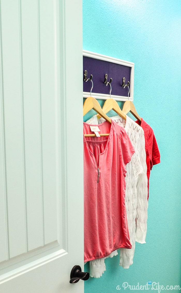 Extra hooks in a laundry room help keep everything organized. Click to see the rest of this bright & happy room!
