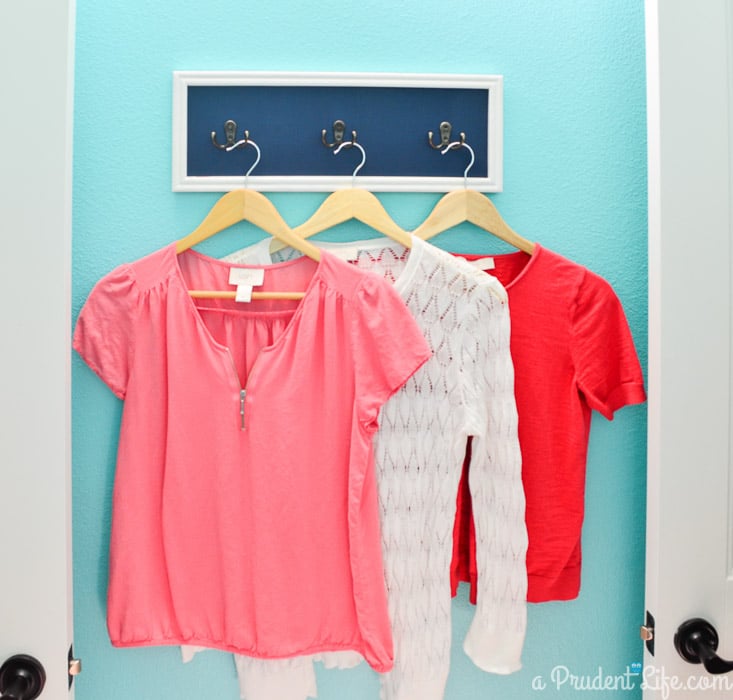 Extra hooks in a laundry room help keep everything organized. Click to see the rest of this bright & happy room!