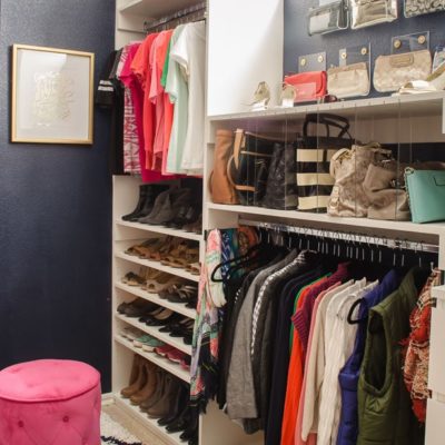 Navy walk-in closet with white shelves and purse storage