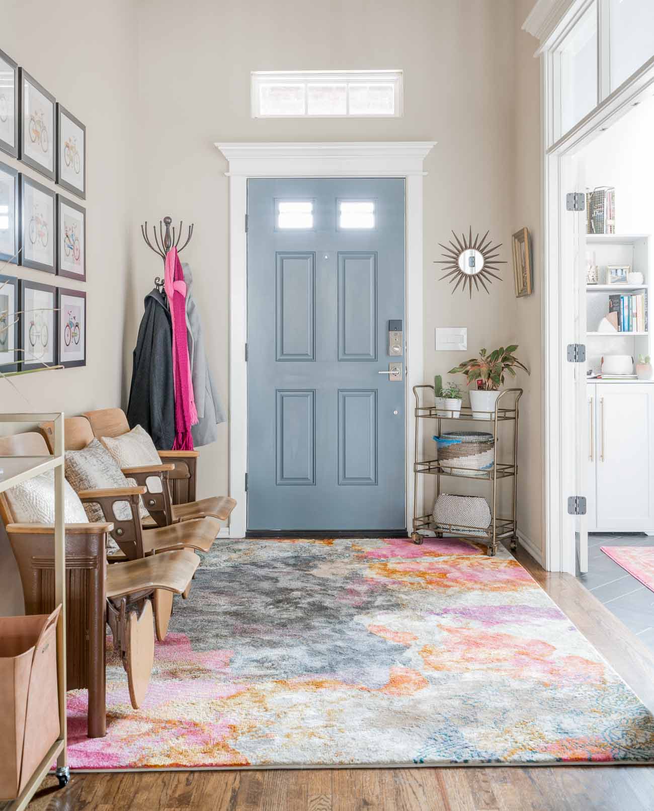 Entryway with gray door, bold rug, and vintage auditorium seating.
