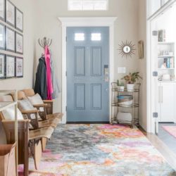 Entry way with gray door, pink rug, and vintage auditorium seats.