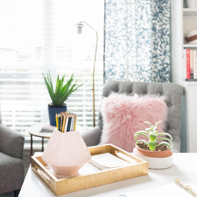 Small pink vase on white desk in feminine office.