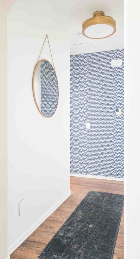 Round mirror on white walls in short hallway