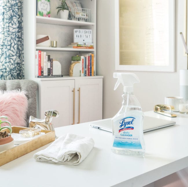 Cleaning a white desk in a feminine office with pretty bookshelves