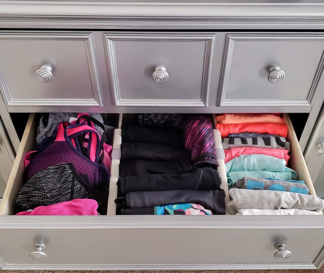 Sports bras, yoga pants, and tank tops organized in a drawer