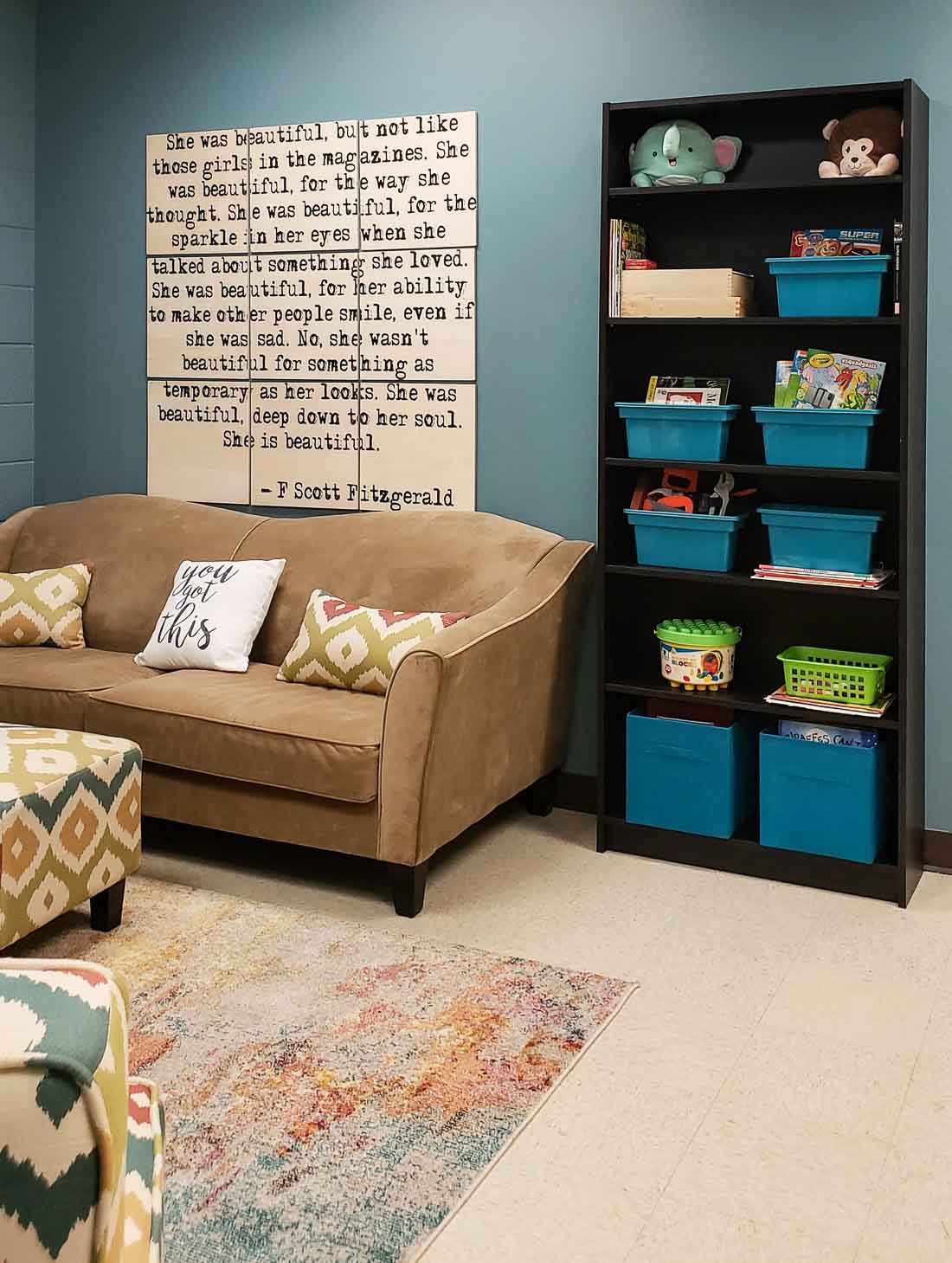 Teal wall and a bookcase full of toys for the kids.