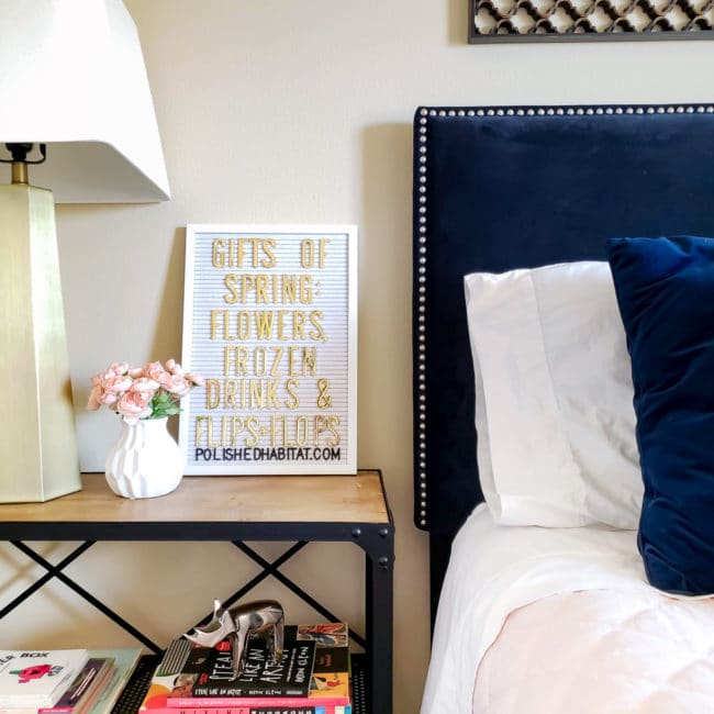 Navy headboard and nightstand with white letterboard and gold lamp