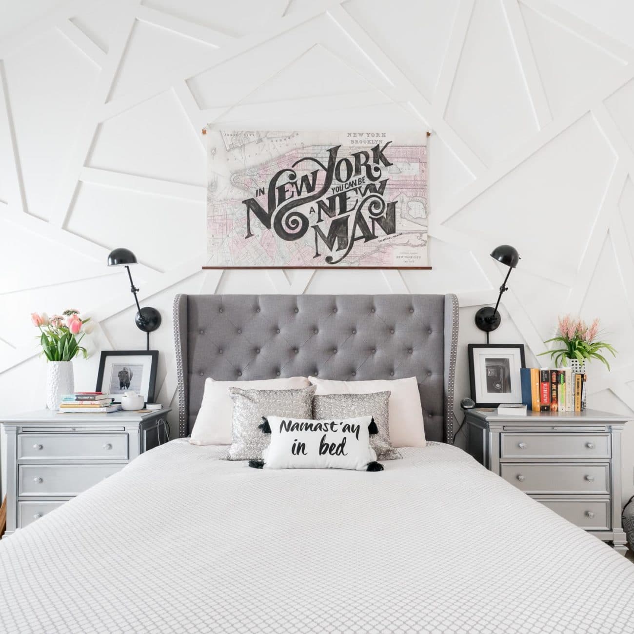 Modern bedroom with white geometric wall and silver nightstands with books