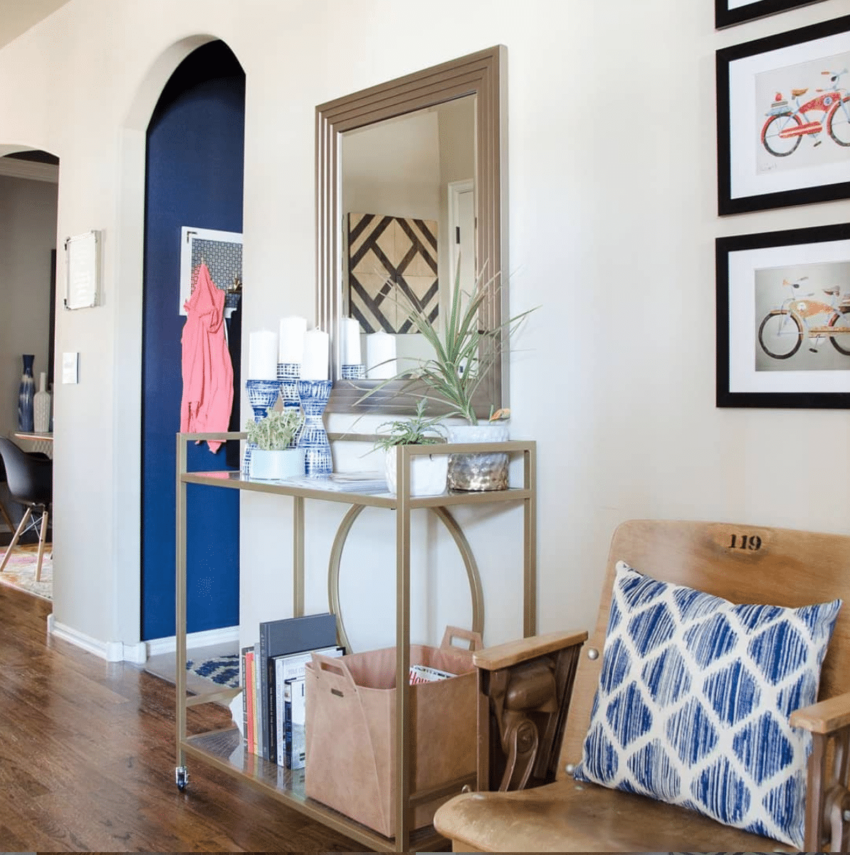 Entry with wood floors and gold bar cart holding books, plants and magazines