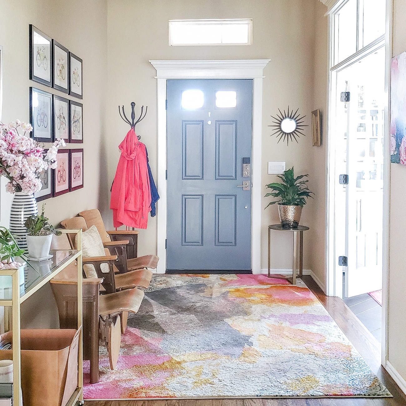 Entryway with bold pink rugh and gray front door. 