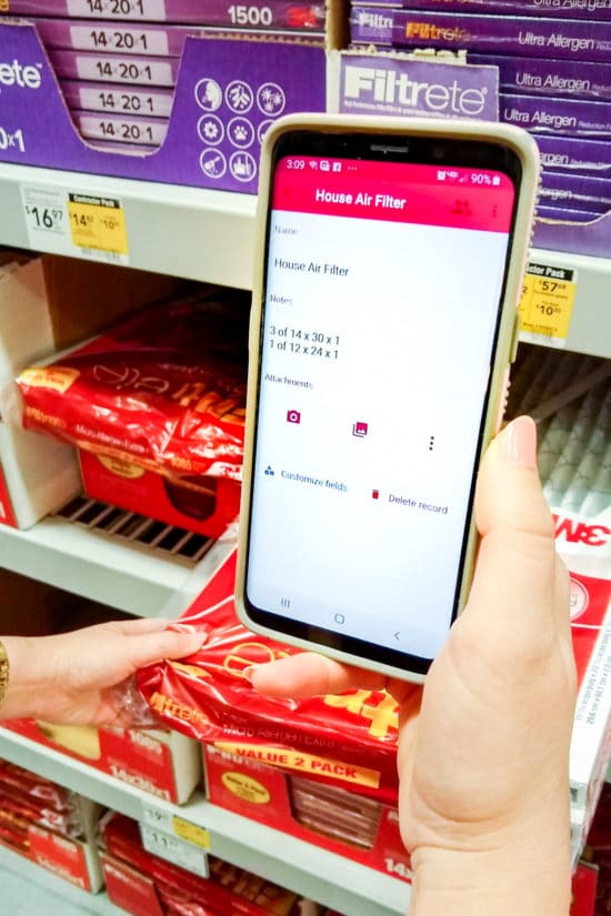 Phone with home air filter sizes on screen in hardware store aisle