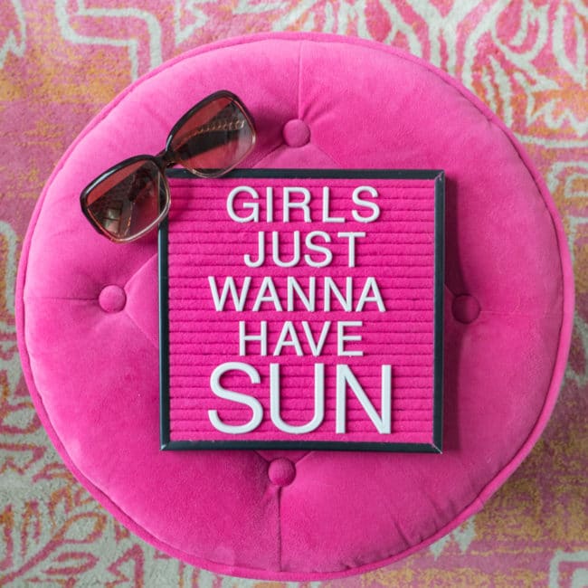 Pink round ottoman with pink letterboard saying "Girls Just Wanna Have Sun"