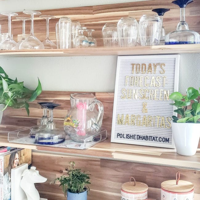 Wood kitchen shelves with glassware and white letter board with gold letters saying "Today's Forecast: Sunshine & Margaritas"