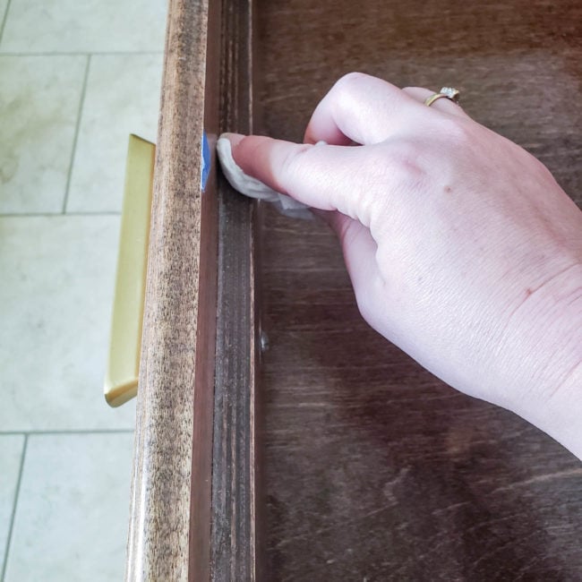 hand with cloth dusting empty bathroom drawer