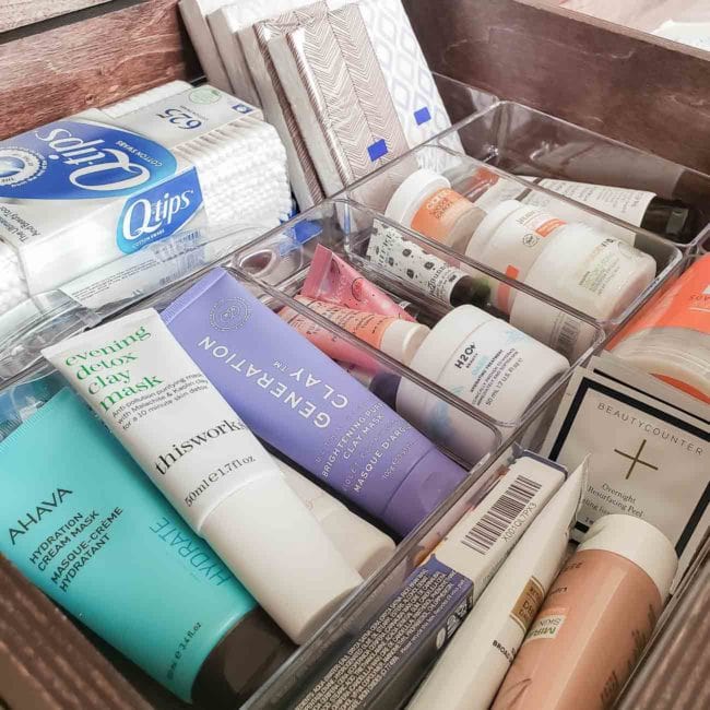 Bathroom products stored in clear organizers inside a drawer