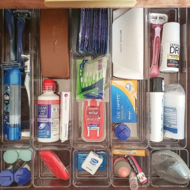 Toiletries stored in clear organizers in bathroom drawer