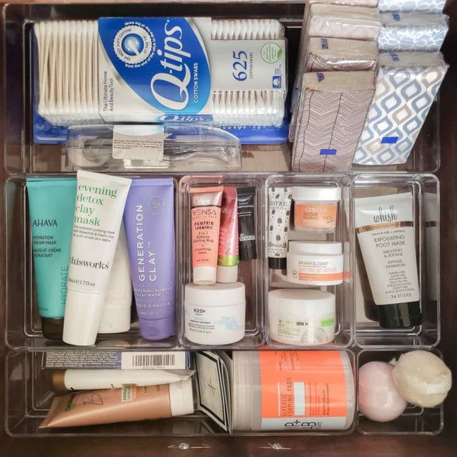 Bathroom products stored in clear organizers inside a drawer