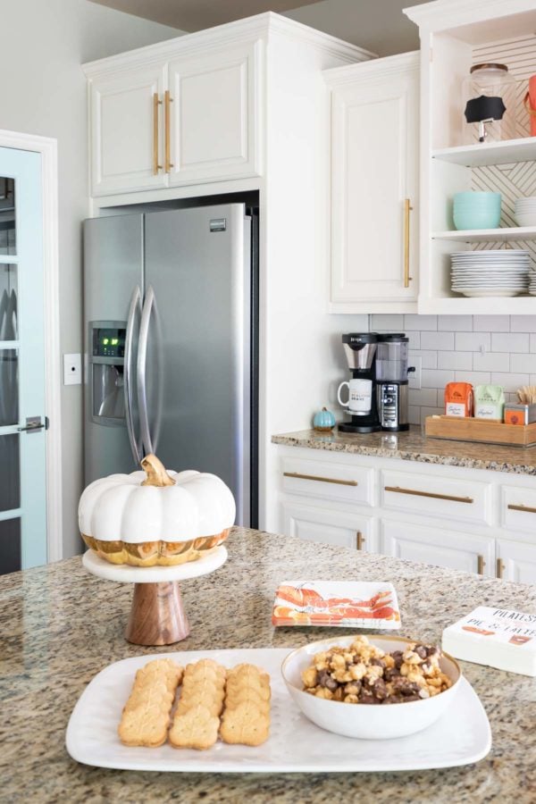 white pumpkin with gold botton on tiered stand in white kitchen 