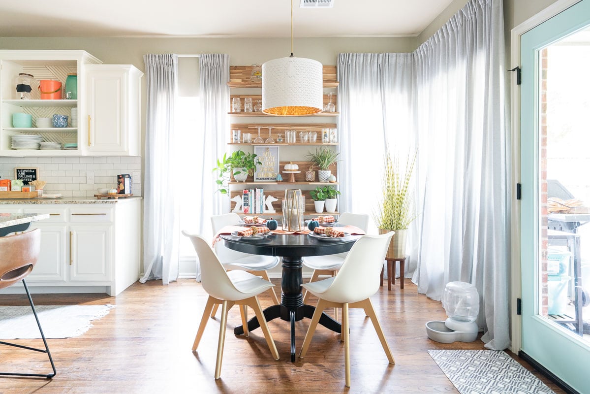 Kitchen nook with white chairs and black table. 