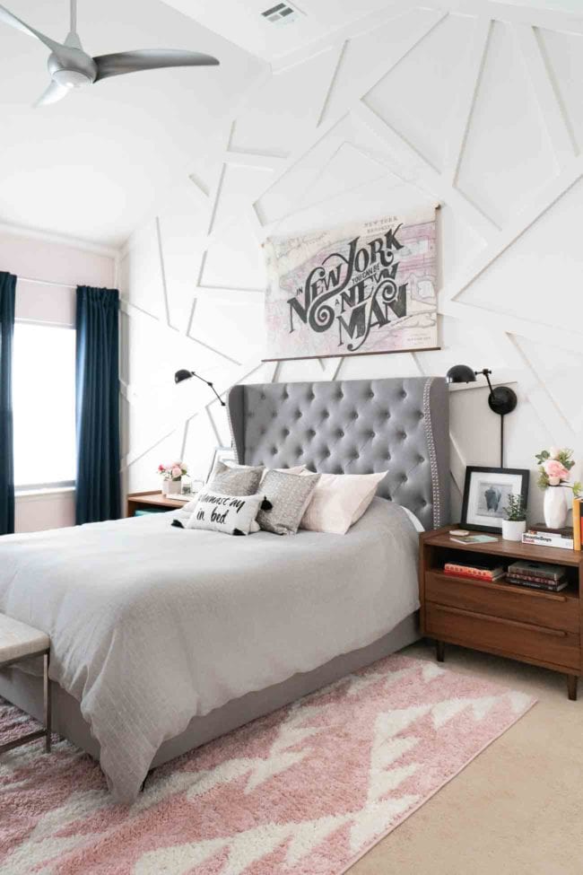 Master bedroom with tall grey  tufted headboard and geometric white accent wall