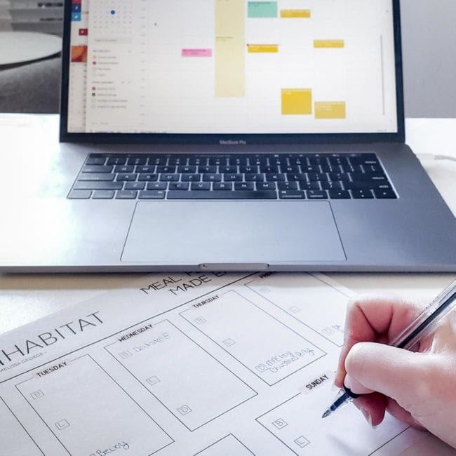 Meal plan printable on desk in front of laptop open to calendar