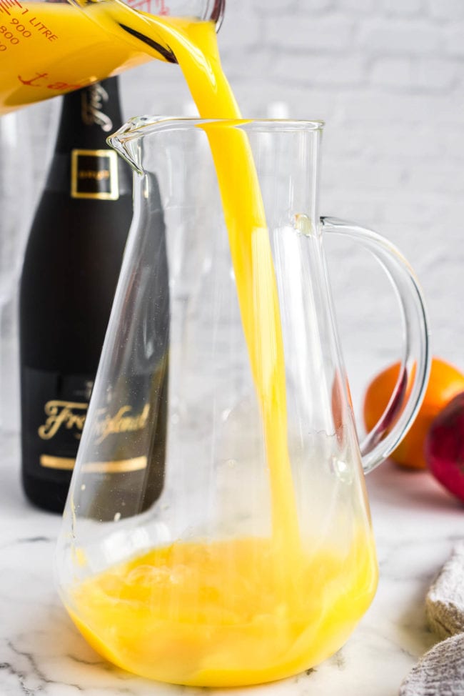 Pouring orange juice into a clear pitcher