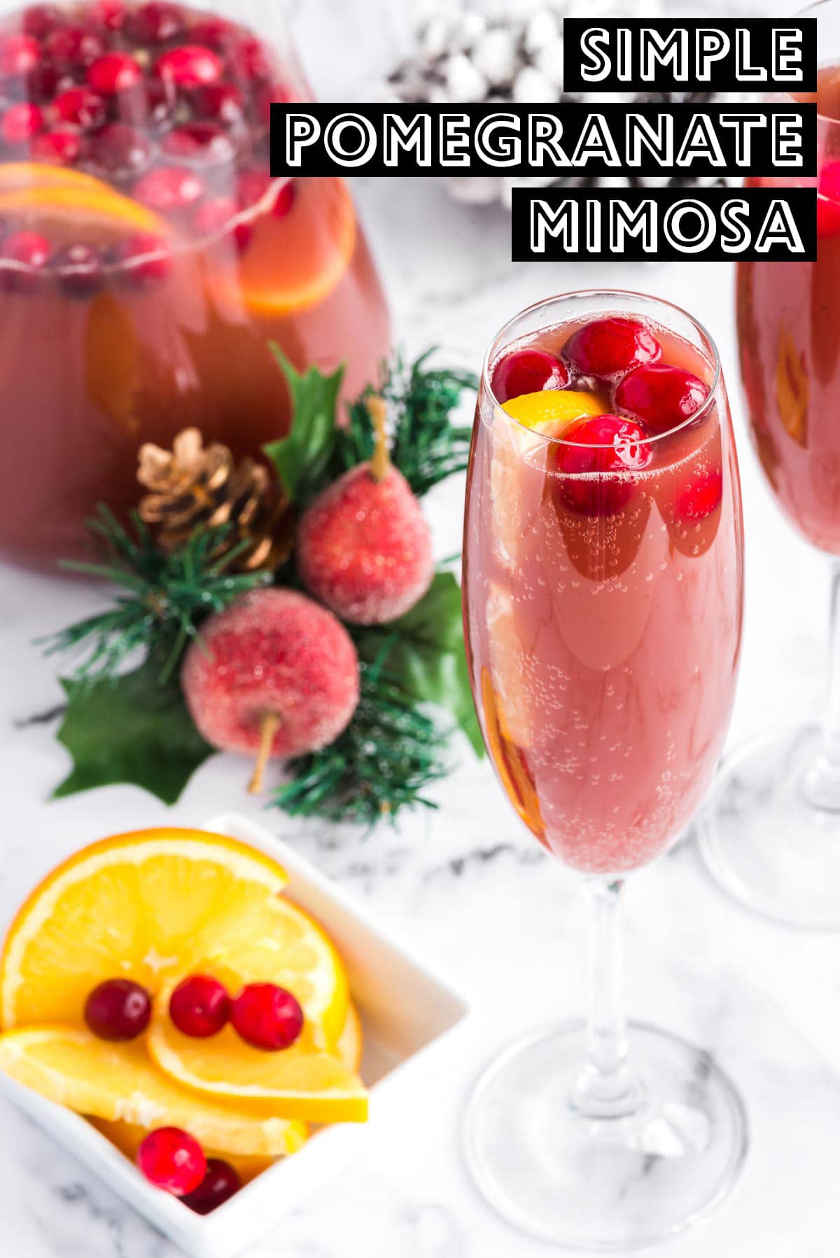 Red pomegranate mimosa in a champagne glass in front of pitcher