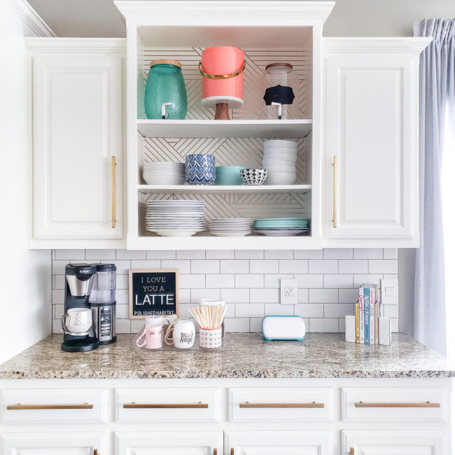 White kitchen cabinets with granite countertop featuring a coffee station, Cricut Joy & cookbooks. 