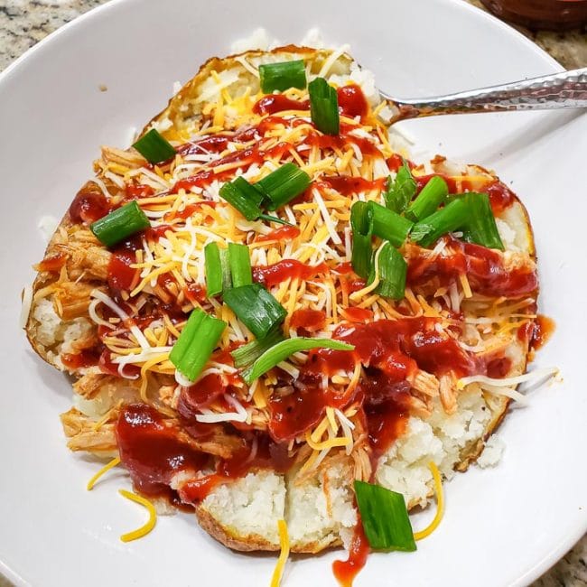 Baked Potato iin White Bowl Covered in BBQ, Cheese & Chives