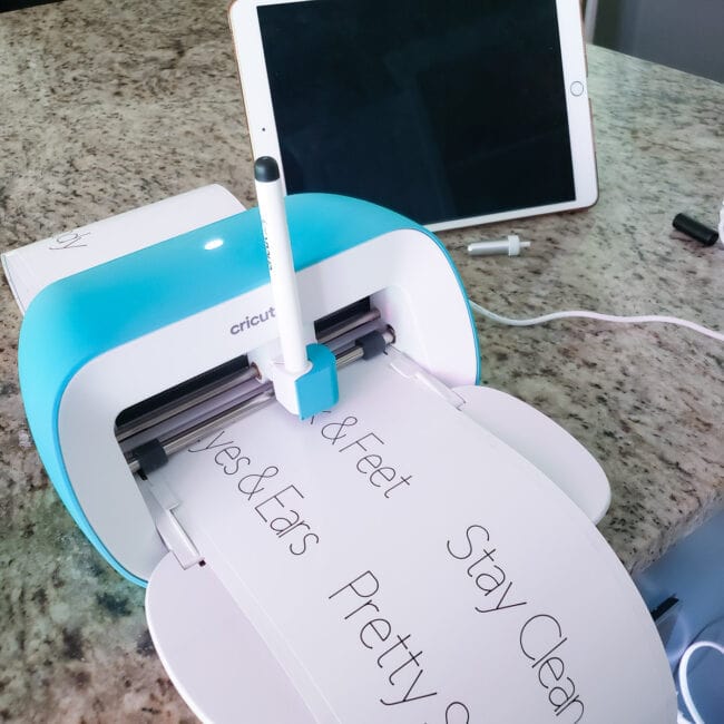 Cricut Joy in use writing on white labels.