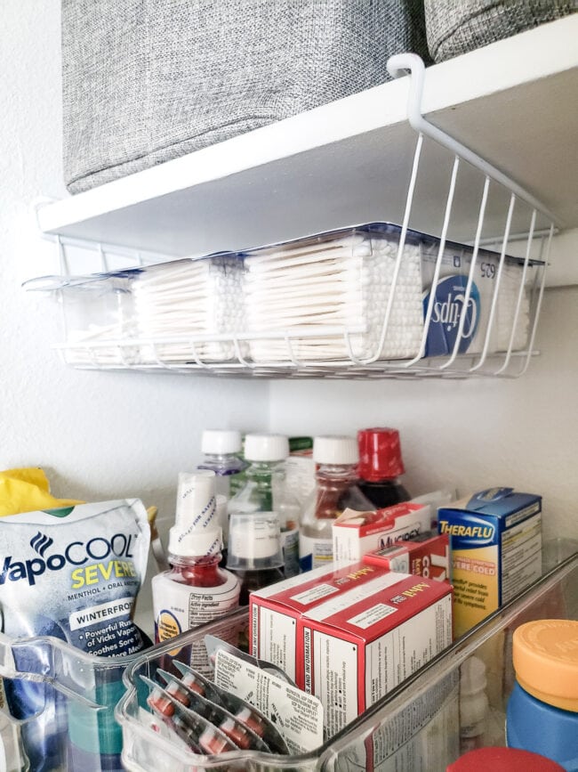 Q-Tip containers in under shelf bin above medicine