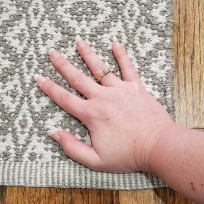 Hand pressng corner of grey and white rug