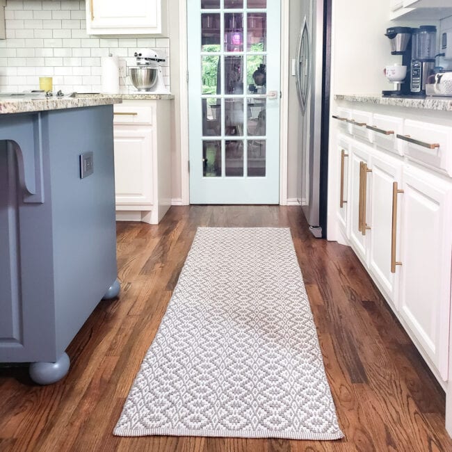 Gray runner on wood floor in white kitchen