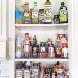 White cabinet full of cooking items like spices, oils, and vinegars