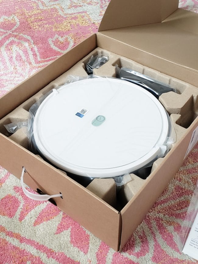 cardboard box with white, circular robot vacuum inside