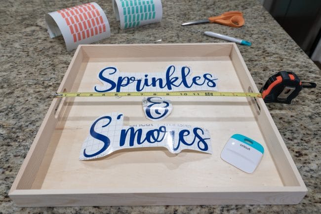 Wood tray with dark blue vinyl ready to be applied reading Sprinkles & S'mores