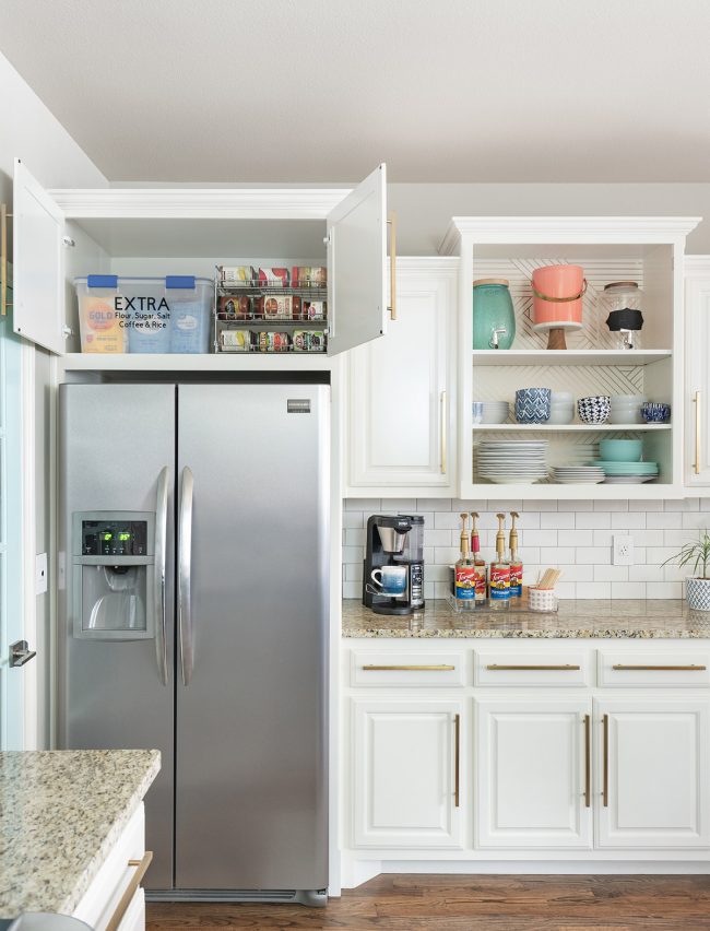 white cabinets & stainless steel fridge with cabine above the fridge open & canned goods inside